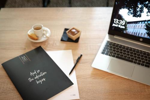 a desk with a laptop and a cup of coffee at La Citadelle Hotel Metz - MGallery Collection in Metz