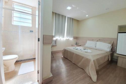 a bedroom with a bed and a toilet and a tv at Pousada Sao Paulo in Vila Muriqui