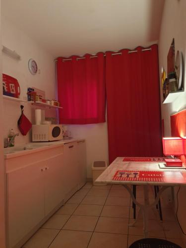 - une cuisine avec des rideaux rouges et une table dans l'établissement Appartement Terrasse - Hypercentre, à Avignon