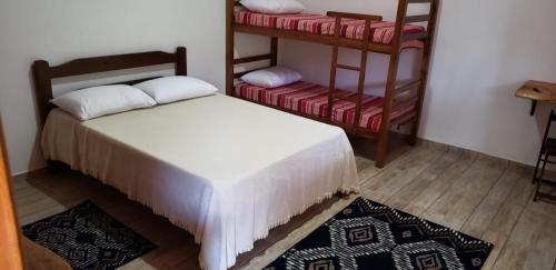 a bedroom with a bed and two bunk beds at Cabana da Montanha - Sítio Pasangas in Santo Antônio do Pinhal
