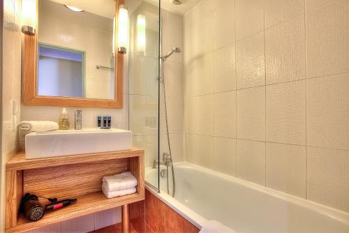 une salle de bain avec un lavabo, une baignoire et un miroir dans l'établissement Appartement Port Prestige - terrasse - piscine - parking, à Antibes