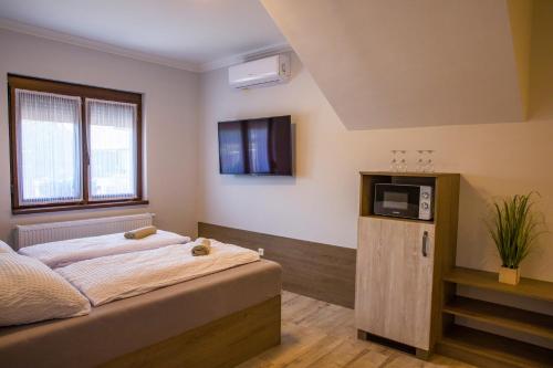 a bedroom with a bed and a tv on the wall at Kukorica Csárda Apartman in Balatonújlak