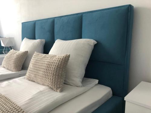 a blue headboard of a bed with white pillows at Apartament Planeta 202 - tylko 100 m do plaży, odnowiony w 2024 in Mielno