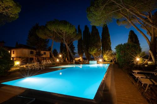 a swimming pool at night with chairs and trees at Agriturismo Pieve Sprenna in Buonconvento