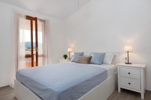 een witte slaapkamer met een bed en een raam bij Sa Prenda in Villasimius