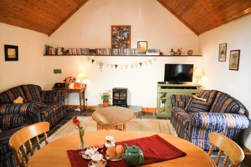 a living room with couches and a table and a tv at Wisteria Cottage in Ballyconnell