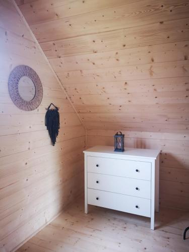 a bedroom with a white dresser in a wooden wall at Domki Dobrogoszcz in Dobrogoszcz