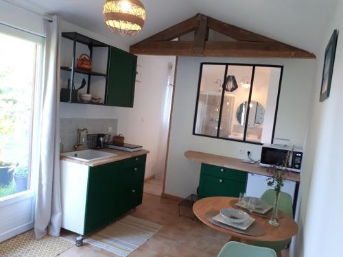 eine Küche mit grünen Schränken, einer Spüle und einem Tisch in der Unterkunft L’escale côté jardin in Saint-Laurent-de-Médoc