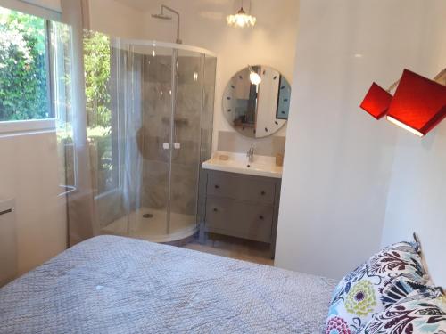 ein Bad mit einer Dusche, einem Waschbecken und einem Bett in der Unterkunft L’escale côté jardin in Saint-Laurent-de-Médoc