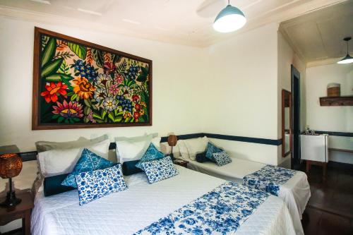 a bedroom with two beds and a painting on the wall at Pousada Bartholomeu in Paraty