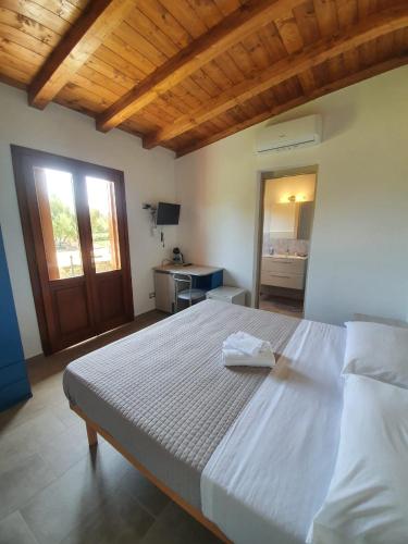 a bedroom with a large white bed with a wooden ceiling at Affittacamere Samar in San Teodoro