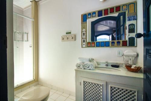 een badkamer met een wastafel, een toilet en een spiegel bij Pousada Bartholomeu in Paraty