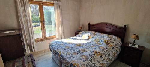 a bedroom with a bed with a floral comforter and a window at Casa de Adobe Remanso del Espíritu in Isla de Maipo
