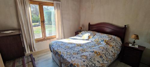 a bedroom with a bed with a floral comforter and a window at Casa de Adobe in Isla de Maipo