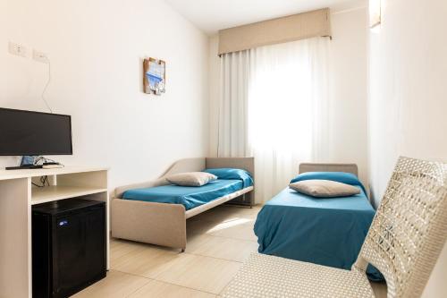 アッリステにあるSTELLA MARINA B&Bのベッド、椅子、テレビが備わる小さな客室です。