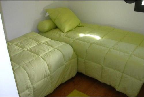 Cama pequeña en habitación con almohada verde en Appartement spacieux 3 chambres, en Génos