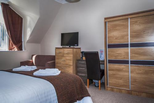 una camera con un letto e un comò con una televisione di Sutherland House a Oban