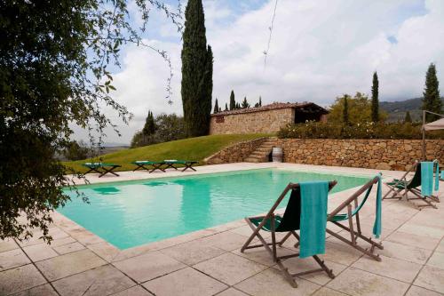a swimming pool with two chairs and a house at Villa Rosano in Greve in Chianti
