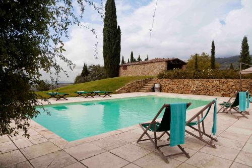 una piscina con due sedie e una casa di Villa Rosano a Greve in Chianti