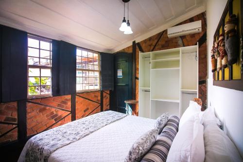 a bedroom with a bed and two windows at Pousada Bartholomeu in Paraty