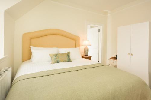 a white bedroom with a large bed with a headboard at Springkell in Eaglesfield