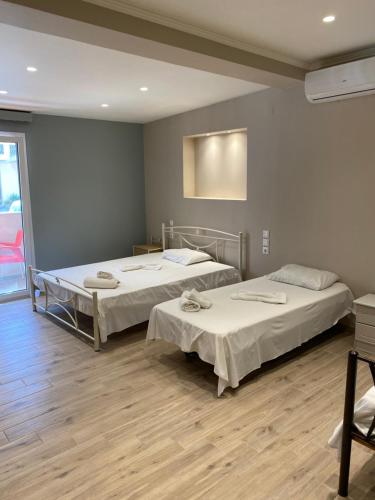 two beds in a room with wooden floors at Studios Artemis in Lefkada Town