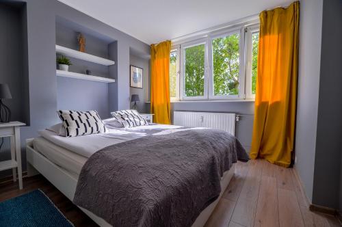 グディニャにあるCITYSTAY Partyzantow Apartmentのベッドルーム1室(黄色のカーテン付きの大型ベッド1台付)