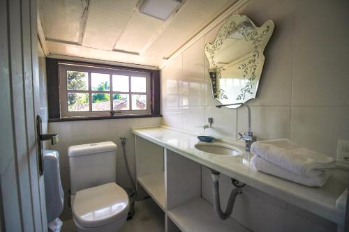 a bathroom with a sink and a toilet and a window at Pousada Bartholomeu in Paraty