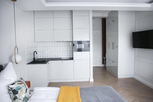 a kitchen with white cabinets and a tv in a room at Zielony Dom in Mielno