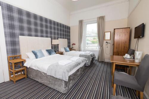 a hotel room with two beds and a television at Edinburgh Rays Guest House in Edinburgh