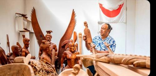 a man standing next to a group of wooden statues at Cabañas Te Maori in Hanga Roa