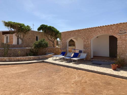 duas cadeiras azuis sentadas num pátio ao lado de um edifício em DAMMUSI JERIMAR em Lampedusa