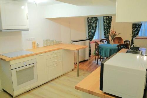 une cuisine avec une table et un homme assis à une table dans l'établissement Gîte de la chapelle, au coeur de la cité médiévale, à Allègre