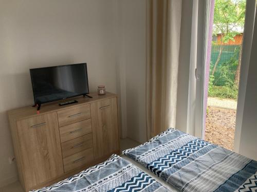 a bedroom with a tv on a dresser with a bed at Apartament 8 in Pobierowo