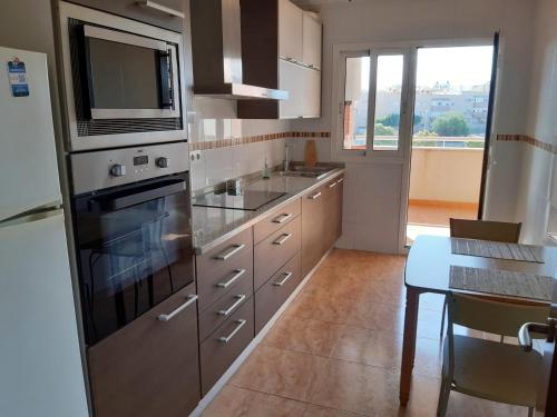 cocina con electrodomésticos de acero inoxidable y mesa en Apartamento moderno con balcón y aparcamiento en Almería - Alborania, en Almería