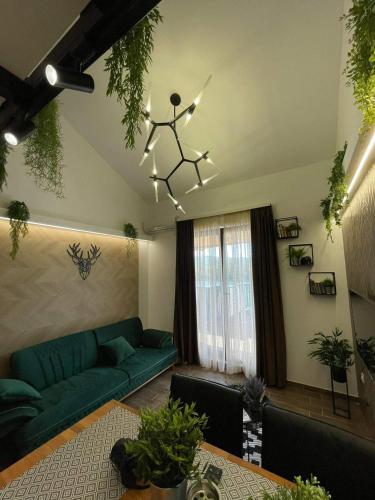 a living room with a green couch and a chandelier at Apartman Plaža Lux in Veliko Gradište