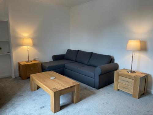 sala de estar con sofá azul y 2 mesas en Premier 3 Bed Flat D, en Broxburn