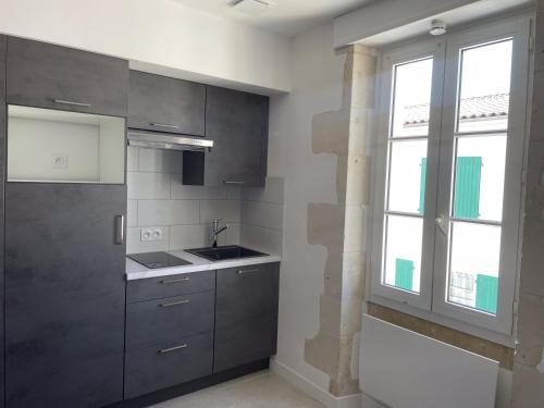 a kitchen with gray cabinets and a window at Bâbord in La Flotte