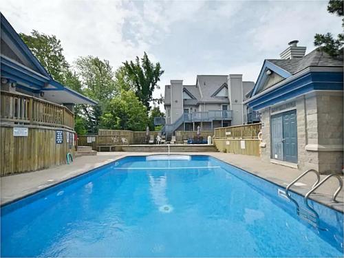 a large blue swimming pool in front of a house at Cozy Studio Loft with 2 Baths Next to Slopes in Blue Mountains