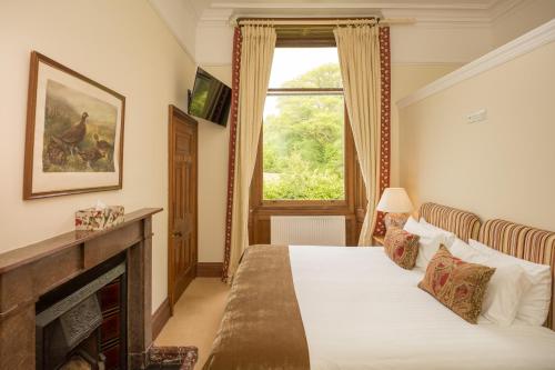 a bedroom with a bed with a fireplace and a window at Springkell in Eaglesfield