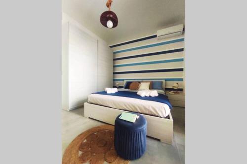 - une chambre avec un lit et un mur rayé bleu et blanc dans l'établissement Casa Angelina a due passi dal mare, à Acireale