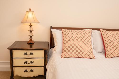a bed with a nightstand with a lamp and two pillows at Springkell in Eaglesfield