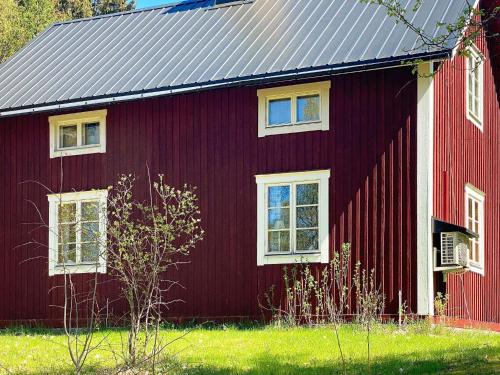 a red barn with white windows on the side of it at 6 person holiday home in TRANSTRAND in Transtrand