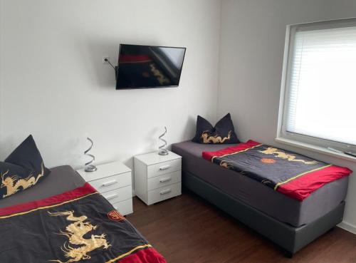 a bedroom with two beds and a tv on the wall at Tollenseheim in Neubrandenburg