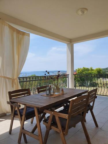 una mesa de madera y sillas en un patio con vistas en Villa Malena en Rab