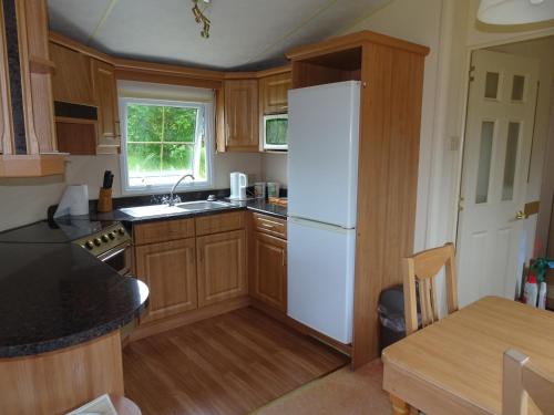 a kitchen with wooden cabinets and a white refrigerator at Asgard in Big Sand