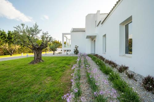 a white house with purple flowers in the yard at Melia Villa Kos with Heated Pool in Kos Town