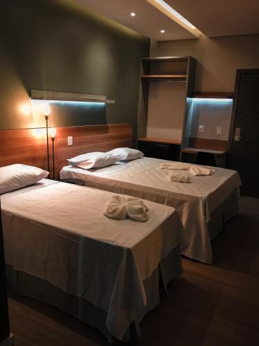 two beds in a hotel room with towels on them at Blue Inn Hotel in Boa Vista