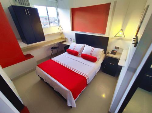 HOTEL COLOURS Cali في كالي: غرفة نوم مع سرير مع وسادتين حمراء