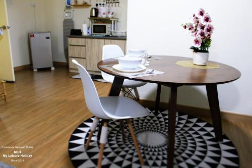a dining room table with two white chairs and a table with flowers at MLH Premier Suites @ Saville Cheras in Cheras